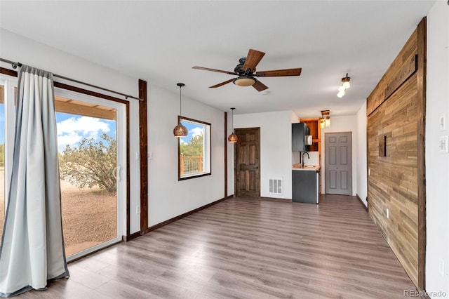 491 Newlin Ridge Rd, Florence, CO 81226 - unfurnished living room with wood finished floors, healthy amount of natural light, a ceiling fan, wood walls, and a sink