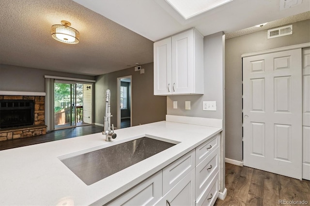 447 S Memphis Way Unit 7, Aurora, CO 80017 - kitchen with dark wood finished floors, white cabinets, light countertops, a fireplace, and open floor plan