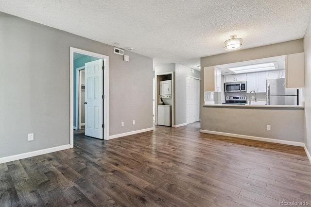 447 S Memphis Way Unit 7, Aurora, CO 80017 - unfurnished living room with stacked washer / drying machine, dark wood-style flooring, and a textured ceiling