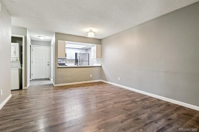 447 S Memphis Way Unit 7, Aurora, CO 80017 - unfurnished living room featuring stacked washer / dryer, dark wood-style floors, and a textured ceiling