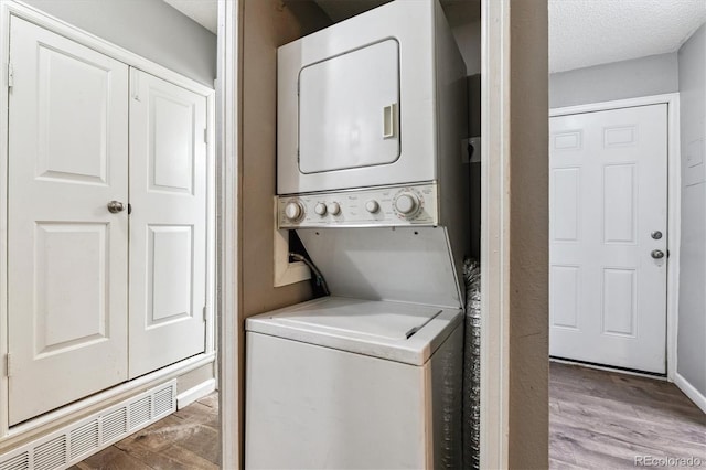 447 S Memphis Way Unit 7, Aurora, CO 80017 - laundry area with stacked washer / dryer, wood finished floors, and a textured ceiling