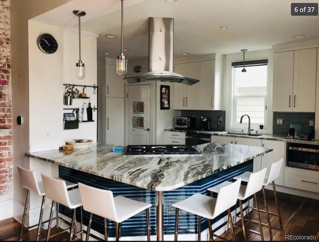 4428 Perry St, Denver, CO 80212 - kitchen with island range hood, gas stovetop, tasteful backsplash, white cabinets, and recessed lighting