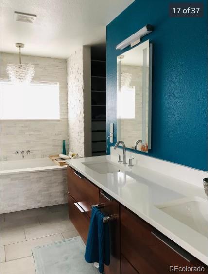 4428 Perry St, Denver, CO 80212 - bathroom with double vanity, a bath, tile patterned floors, a chandelier, and a textured wall