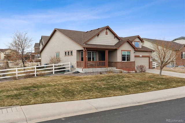 view of front of property with driveway, fence, covered porch, a front yard, and brick siding