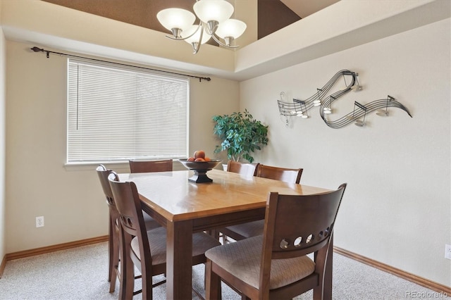 carpeted dining space featuring baseboards and a notable chandelier