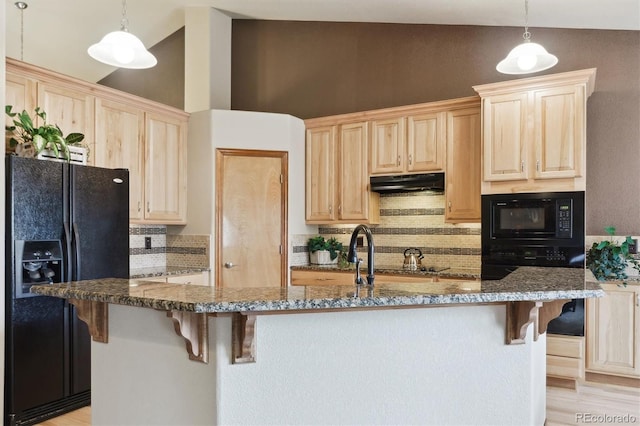 kitchen featuring light brown cabinets, under cabinet range hood, a kitchen bar, lofted ceiling, and black appliances