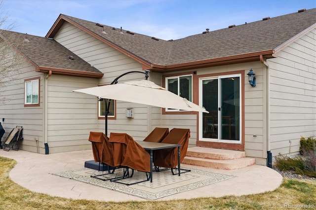 rear view of property featuring a patio and a shingled roof