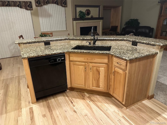 kitchen with light wood-style flooring, dishwasher, light stone countertops, and a sink