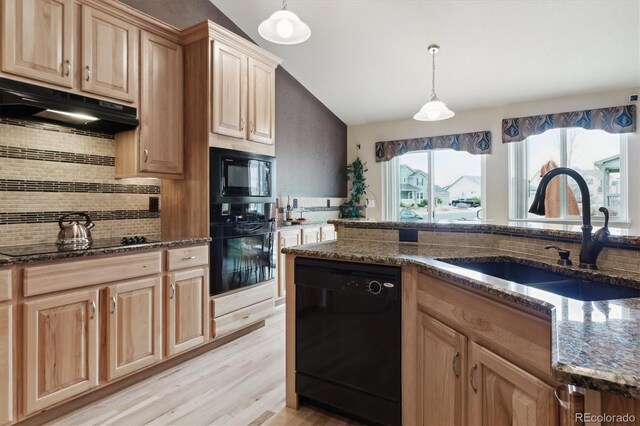 kitchen featuring under cabinet range hood, black appliances, dark stone countertops, and a sink