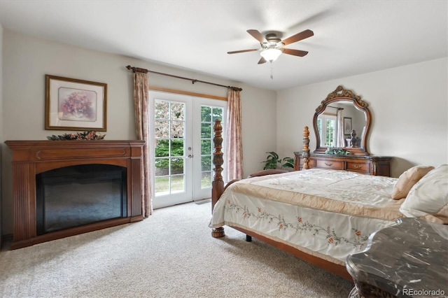 carpeted bedroom with access to exterior, a glass covered fireplace, and ceiling fan