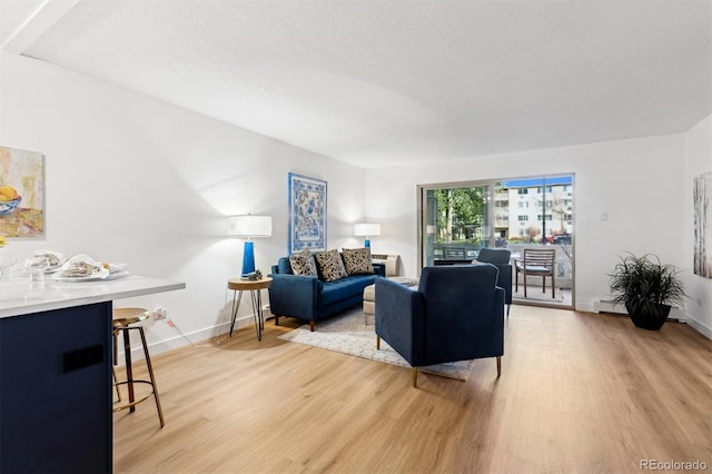 living room featuring baseboard heating, a textured ceiling, and light wood-type flooring