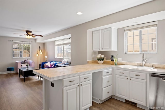 1343 Valentia St, Denver, CO 80220 - kitchen featuring stainless steel dishwasher, a peninsula, white cabinetry, a ceiling fan, and healthy amount of natural light