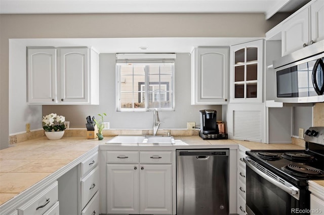 1343 Valentia St, Denver, CO 80220 - kitchen with stainless steel appliances, white cabinetry, glass insert cabinets, and tile counters