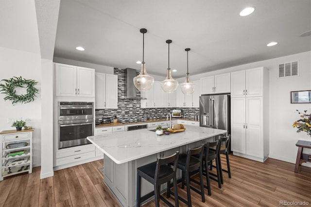14102 Night Owl Ln, Parker, CO 80134 - kitchen with stainless steel appliances, wall chimney range hood, white cabinets, tasteful backsplash, and recessed lighting