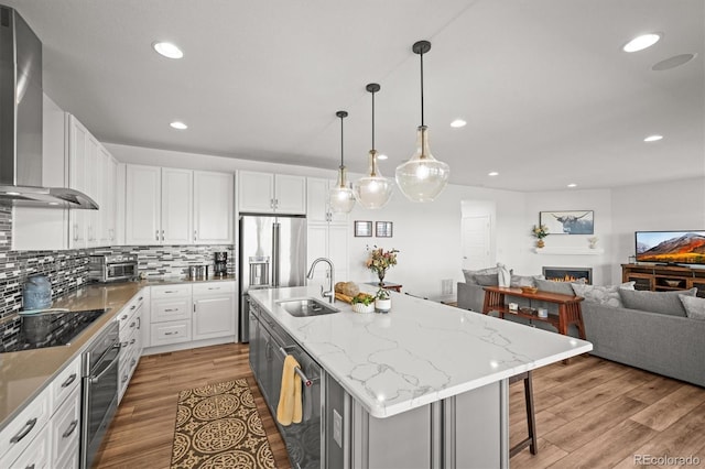 14102 Night Owl Ln, Parker, CO 80134 - kitchen featuring wall chimney range hood, stainless steel appliances, a sink, light wood-style flooring, and open floor plan
