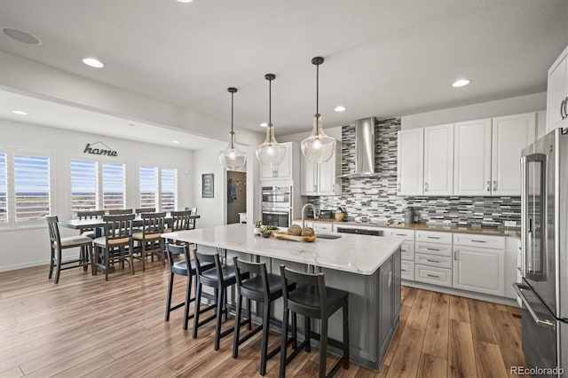 14102 Night Owl Ln, Parker, CO 80134 - kitchen with wall chimney exhaust hood, appliances with stainless steel finishes, a sink, wood finished floors, and backsplash