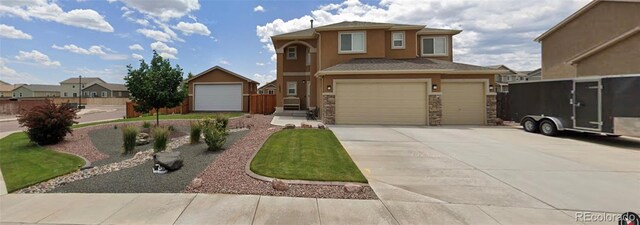 10202 Abrams Dr, Colorado Springs, CO 80925 - view of front facade with concrete driveway, stucco siding, a garage, and stone siding