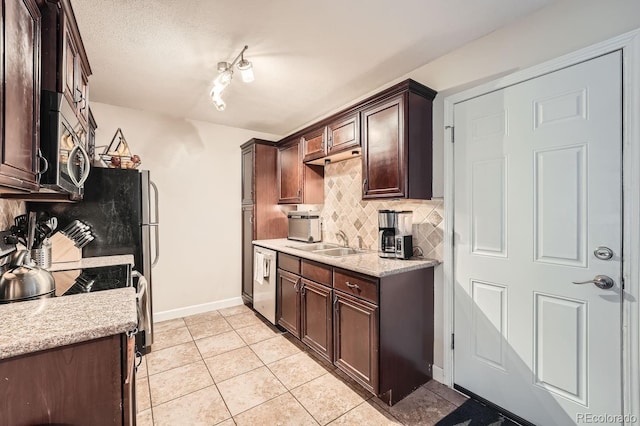 kitchen with sink, appliances with stainless steel finishes, light tile patterned flooring, light stone counters, and dark brown cabinetry