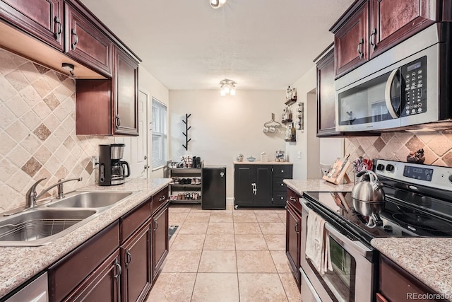 kitchen featuring light stone countertops, sink, decorative backsplash, light tile patterned flooring, and appliances with stainless steel finishes