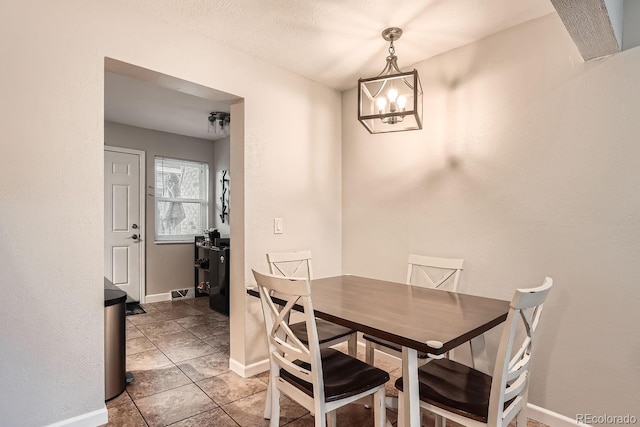 dining area featuring a textured ceiling, tile patterned floors, and a notable chandelier