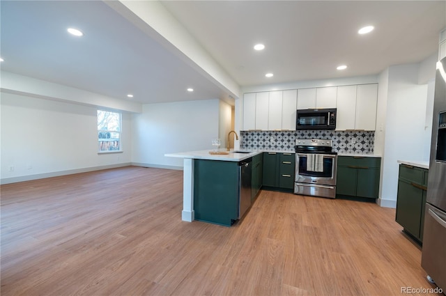 kitchen with kitchen peninsula, stainless steel appliances, sink, white cabinets, and light hardwood / wood-style floors