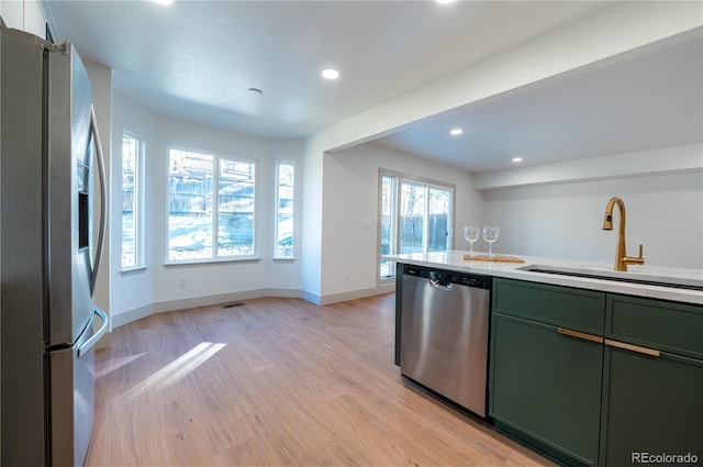 kitchen featuring sink, light hardwood / wood-style flooring, green cabinetry, and appliances with stainless steel finishes