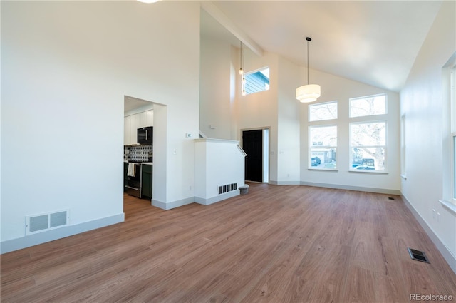 unfurnished living room featuring high vaulted ceiling and light hardwood / wood-style floors