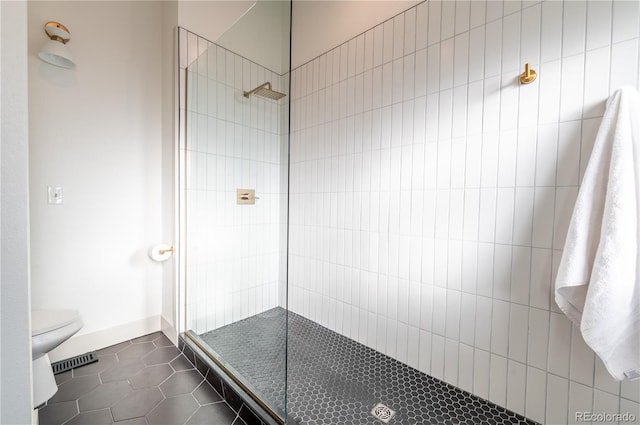 bathroom featuring tile patterned floors, a tile shower, and toilet