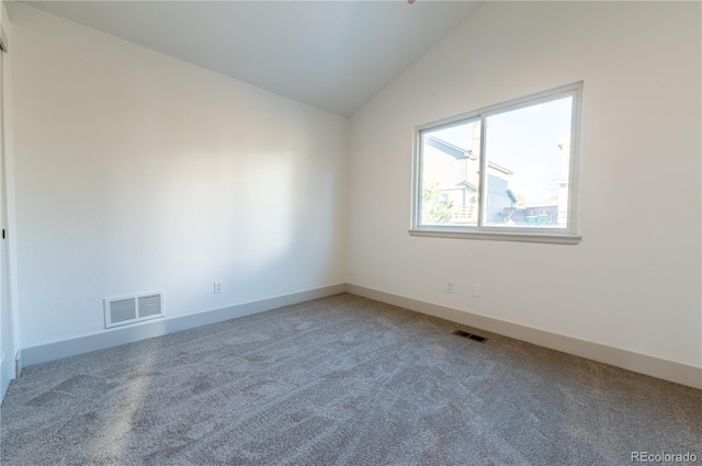 carpeted spare room with vaulted ceiling