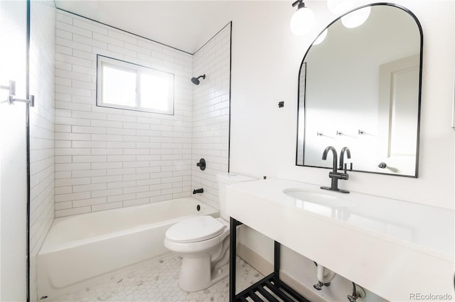 full bathroom featuring tile patterned floors, toilet, tiled shower / bath, and sink