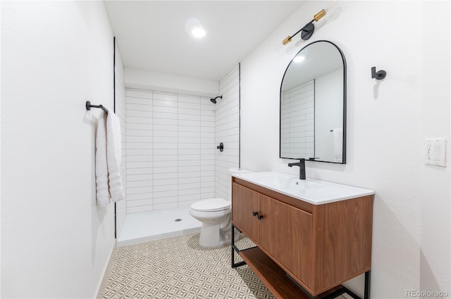 bathroom with a tile shower, tile patterned flooring, vanity, and toilet