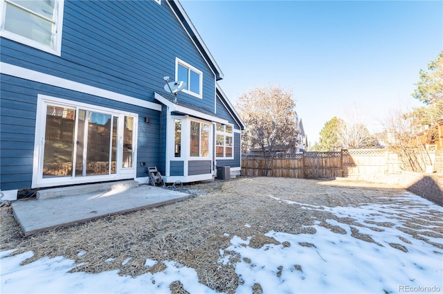 snow covered rear of property featuring central AC unit and a patio