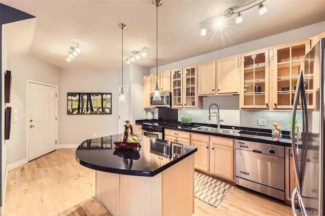 kitchen with light wood-type flooring, appliances with stainless steel finishes, sink, and pendant lighting