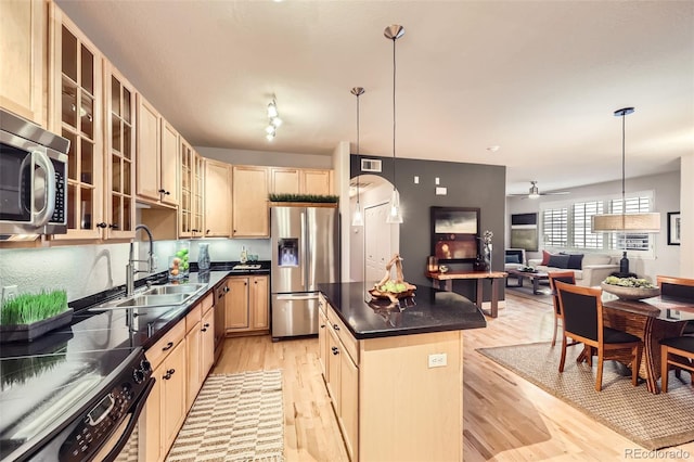 kitchen featuring ceiling fan, appliances with stainless steel finishes, light wood-type flooring, a kitchen island, and pendant lighting