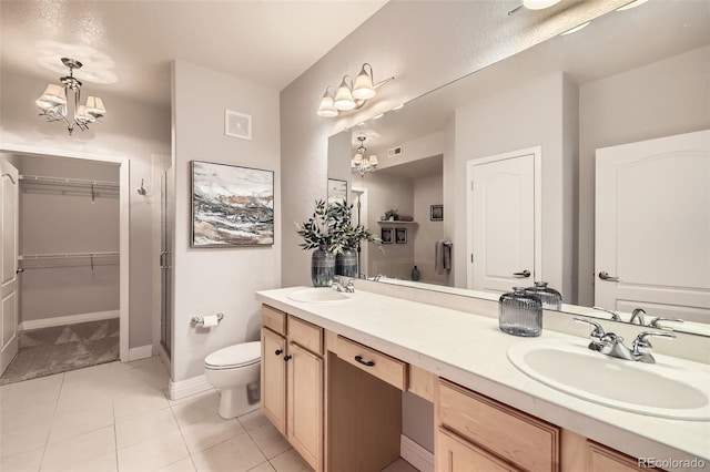 bathroom with toilet, vanity, tile patterned flooring, an inviting chandelier, and a shower with shower door