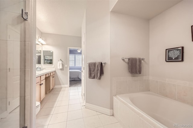 bathroom featuring tiled bath, tile patterned floors, vanity, and toilet