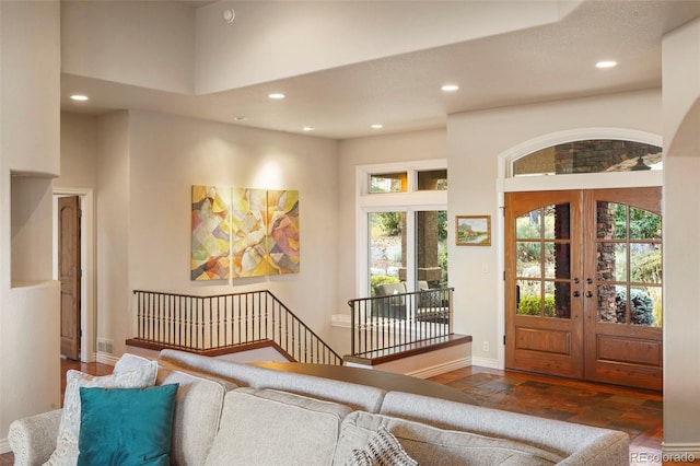 foyer with a towering ceiling, plenty of natural light, dark wood-type flooring, and french doors