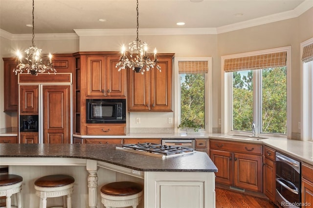 kitchen with ornamental molding, built in appliances, a kitchen breakfast bar, and dark hardwood / wood-style flooring