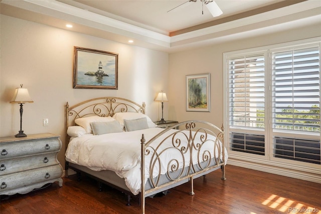 bedroom with ceiling fan, dark hardwood / wood-style floors, and a raised ceiling