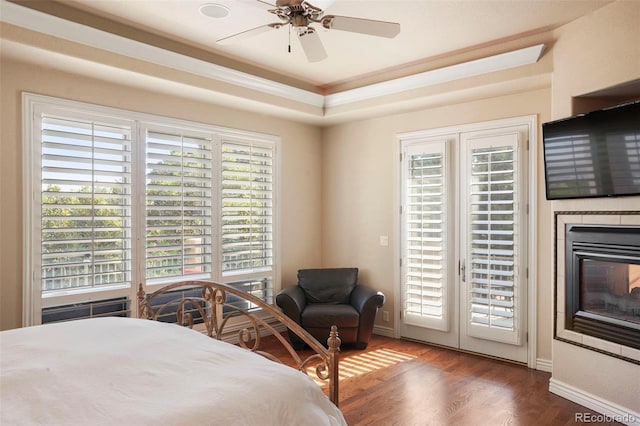 bedroom with dark wood-type flooring, a tray ceiling, access to exterior, and ceiling fan