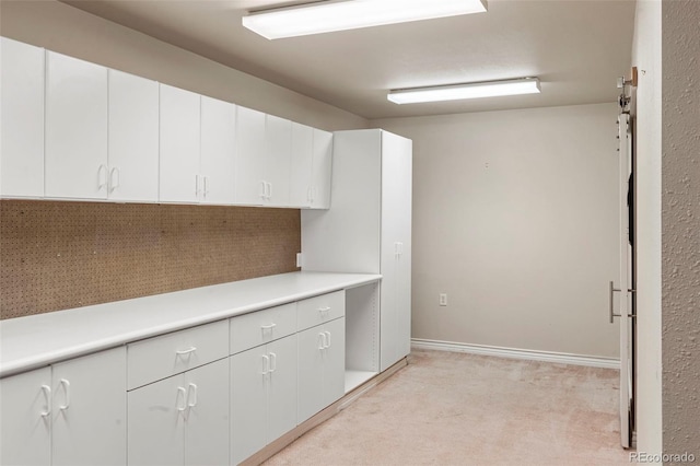 kitchen with light colored carpet and white cabinetry