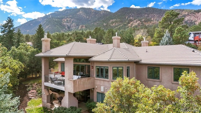 back of property with a mountain view and a balcony