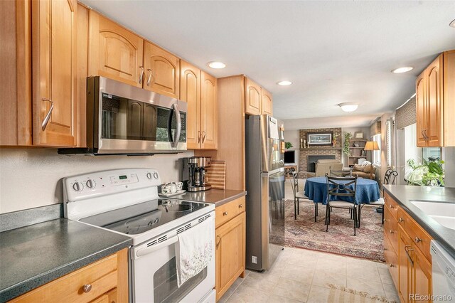 kitchen featuring light tile patterned floors, a brick fireplace, and stainless steel appliances