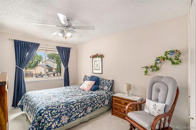 carpeted bedroom featuring ceiling fan and a textured ceiling