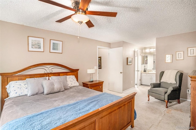 bedroom featuring a textured ceiling, ceiling fan, light colored carpet, and ensuite bath