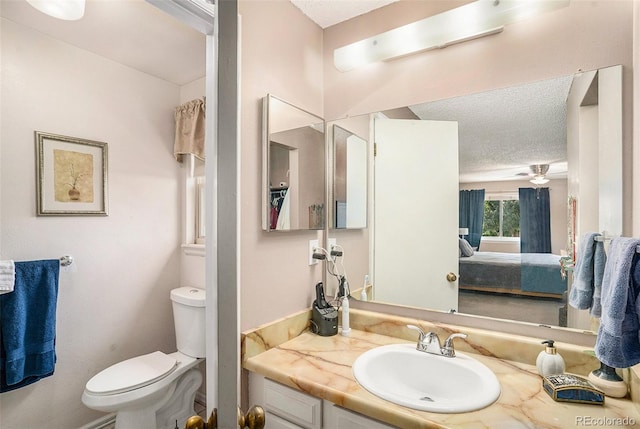 bathroom featuring ceiling fan, vanity, toilet, and a textured ceiling