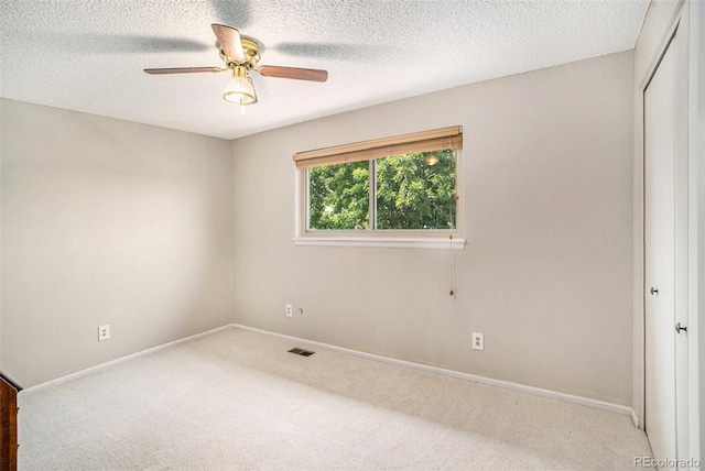 carpeted empty room featuring ceiling fan and a textured ceiling