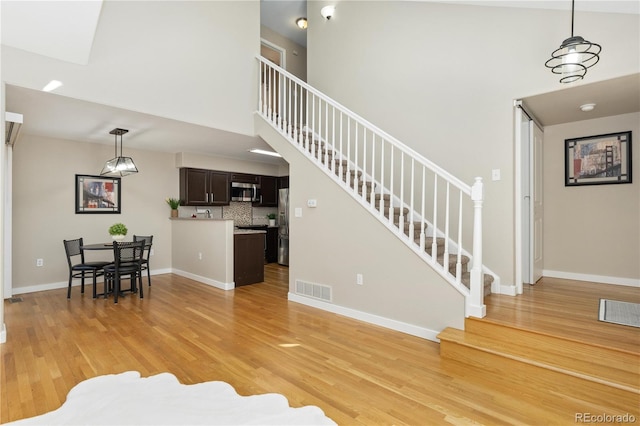 living room with a towering ceiling and light hardwood / wood-style flooring