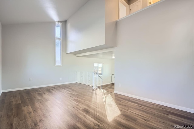 unfurnished living room featuring dark wood-style flooring and baseboards