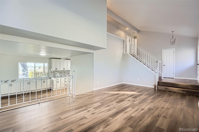 unfurnished living room with stairway, baseboards, wood finished floors, and lofted ceiling
